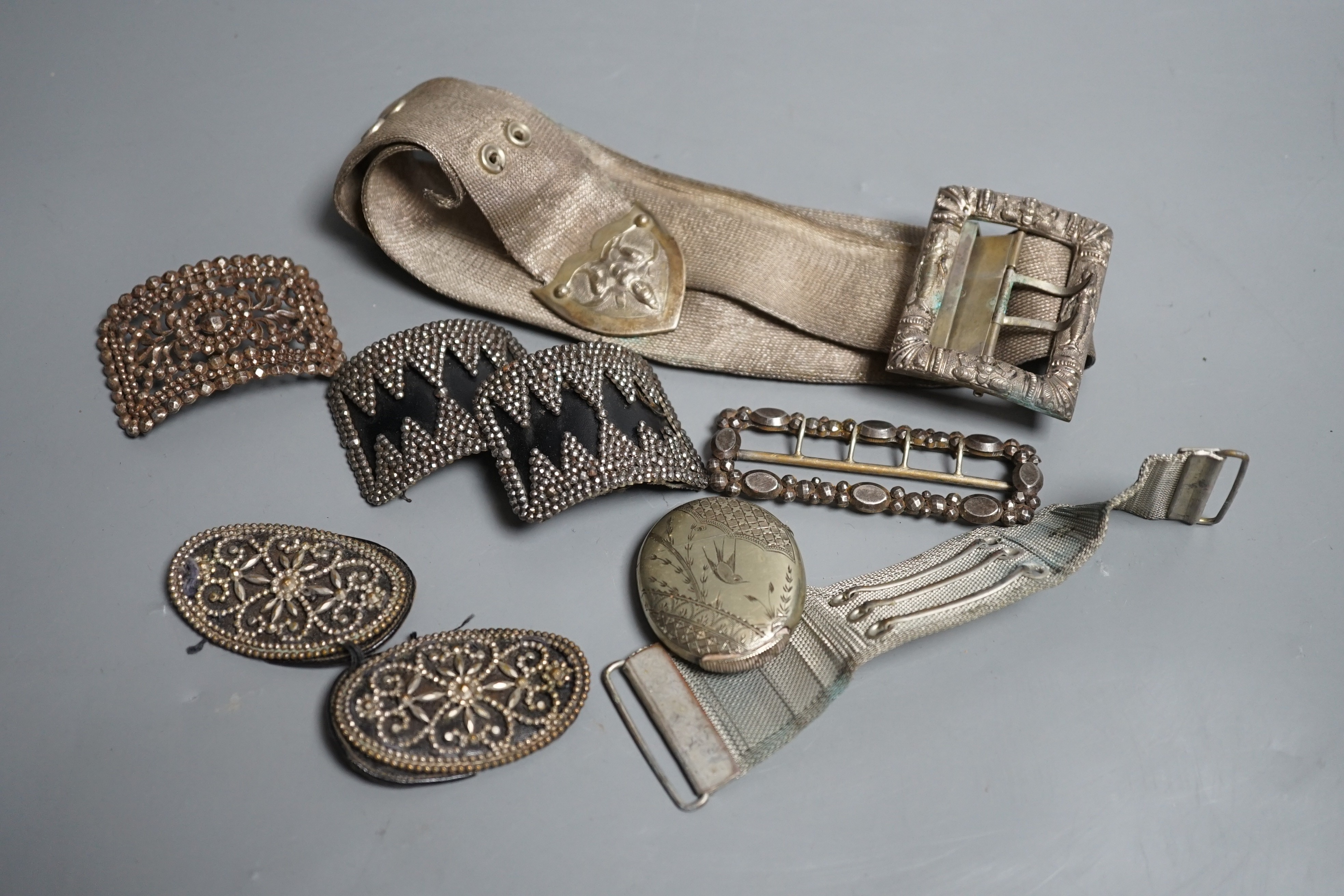 An Indian metal belt, four assorted metal shoe buckles and an aesthetic engraved silver plated vesta case.